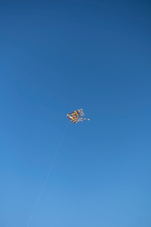 Free A vibrant kite soaring high in a cloudless blue sky, capturing a carefree moment. Stock Photo