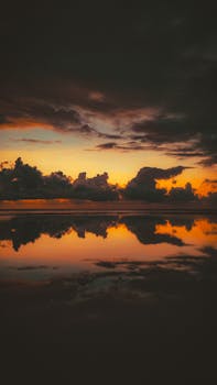 A breathtaking view of the sky and clouds reflecting on the ocean's surface during the golden hour.