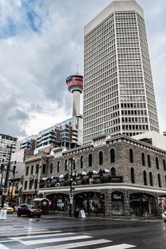 Street view in downtown Calgary featuring the iconic Calgary Tower against a cloudy sky.