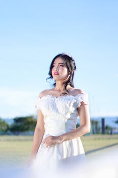 户外阳光明媚，一位美丽的新娘身着白色婚纱，优雅地摆着姿势