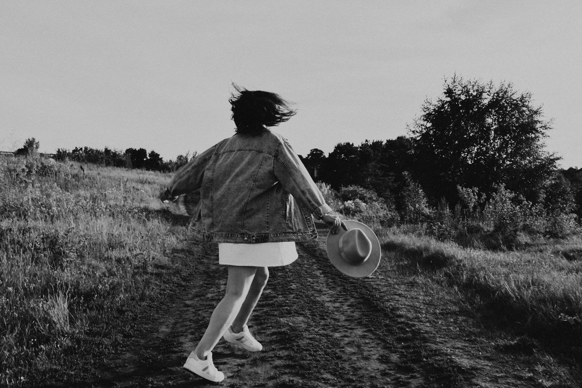 A young girl twirls joyfully outdoors on a sunny day, captured in black and white.