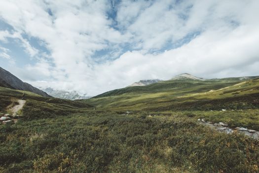 Expansive mountain landscape with green meadows under a partly cloudy sky. Tranquil and scenic view.