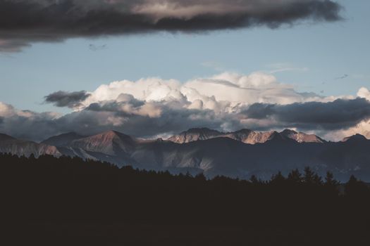 Capture of mountain range with dramatic clouds and evening light, showcasing nature's beauty.