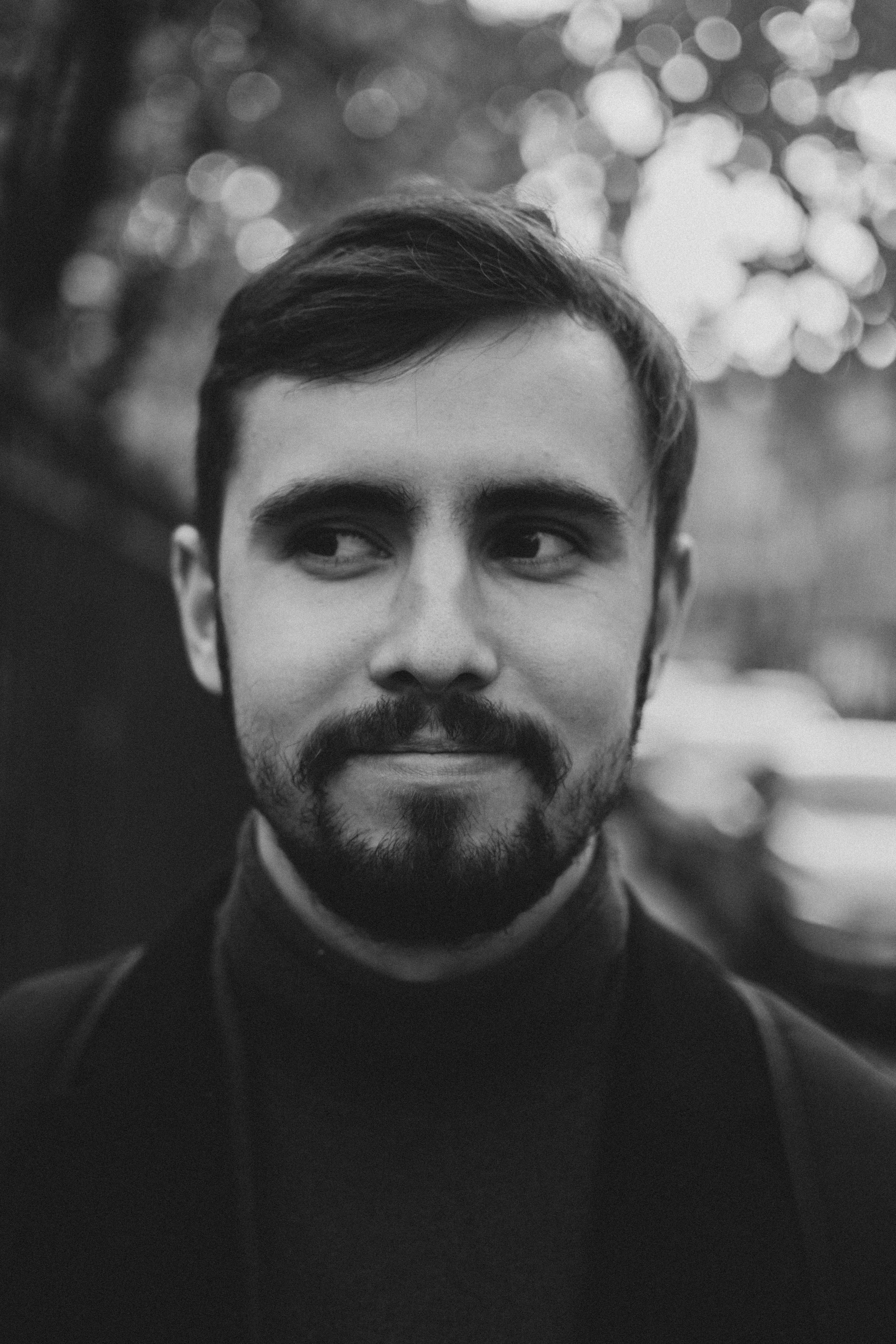 Artistic black and white portrait of a young bearded man with a daring look.