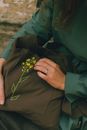Womans hands holding olive colour textile bag with embroidered yellow flower