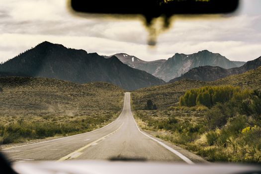 Scenic drive through a mountainous region captured through a car windshield.