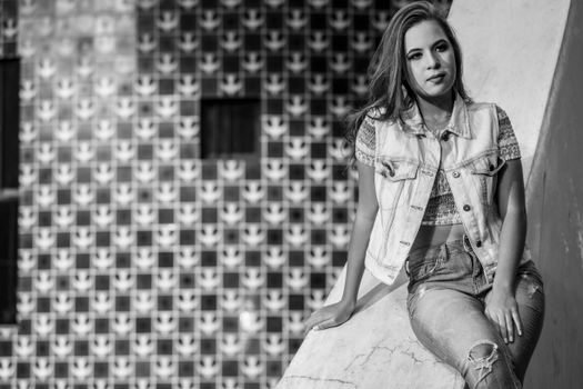 Stylish woman in denim vest posing outdoors in monochrome setting.
