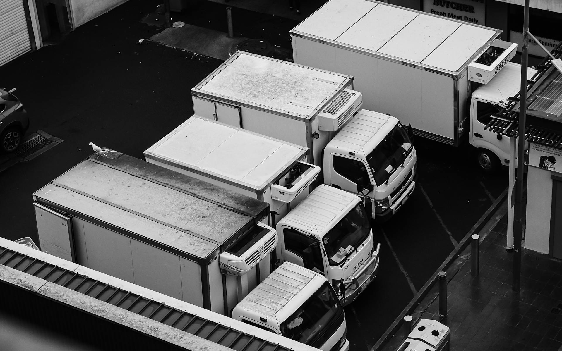 Monochrome aerial shot of commercial trucks parked in a lot, emphasizing industrial design.