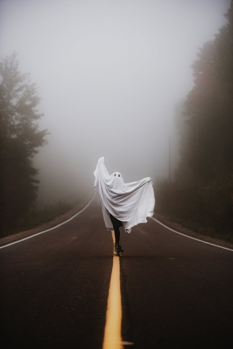 Person In Ghost Costume Dancing On Empty Foggy Road