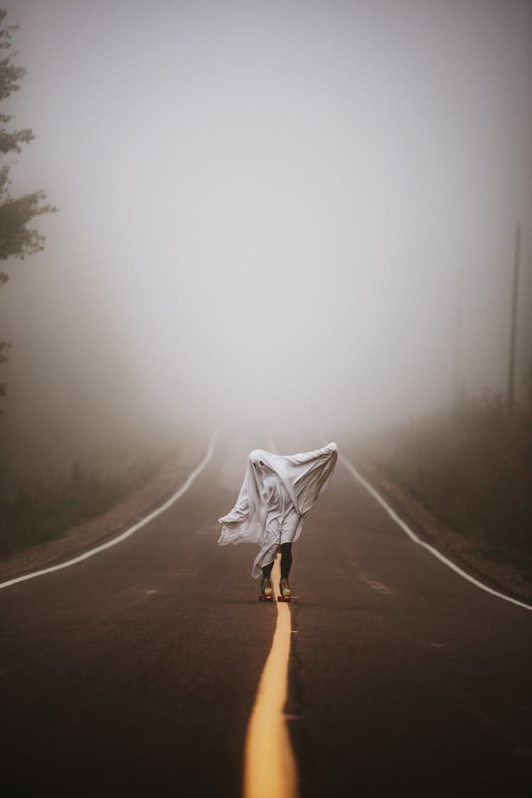 Person In Ghost Costume Skating On Empty Road