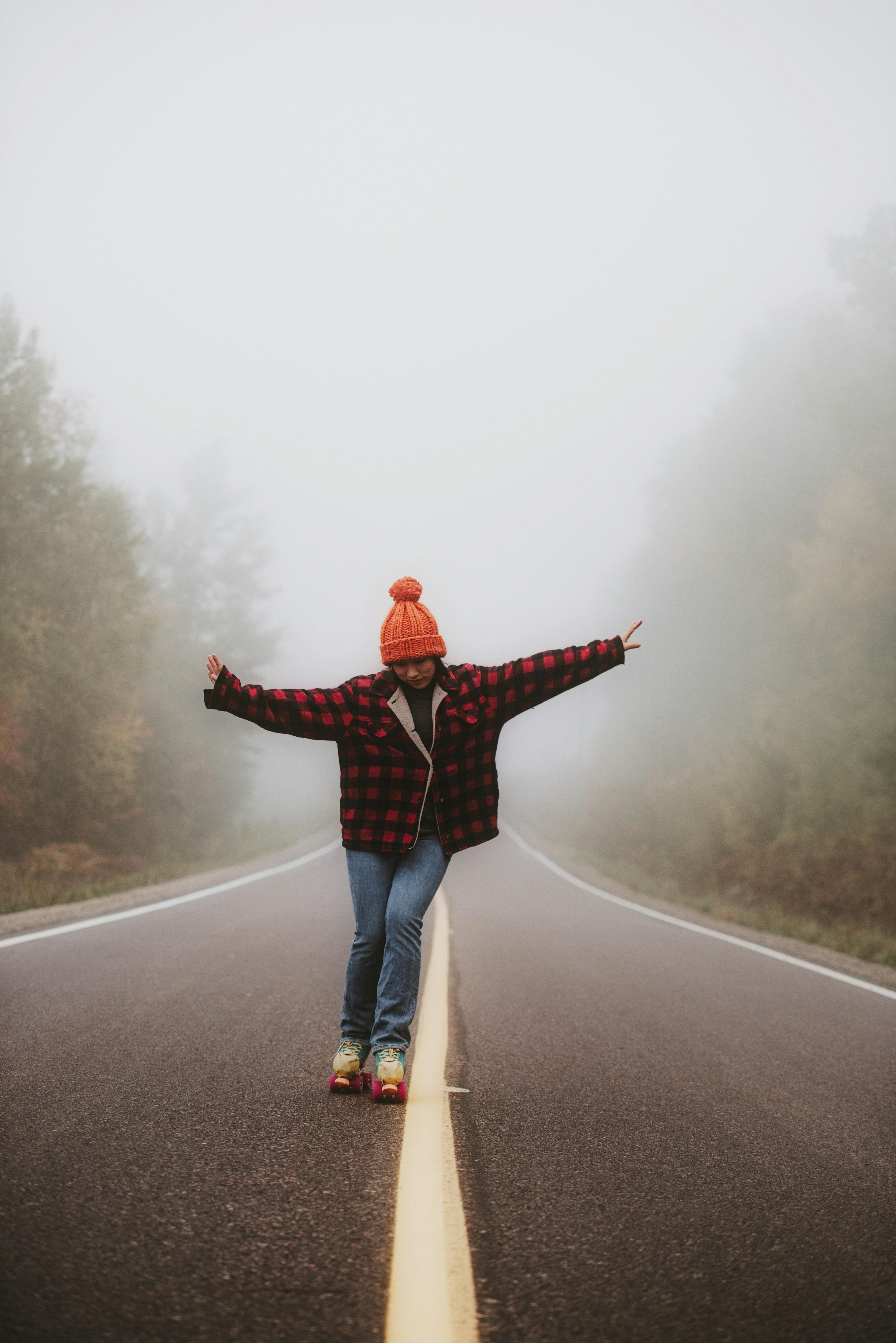 Woman standing on empty road with arms stretched out · Free Stock Photo