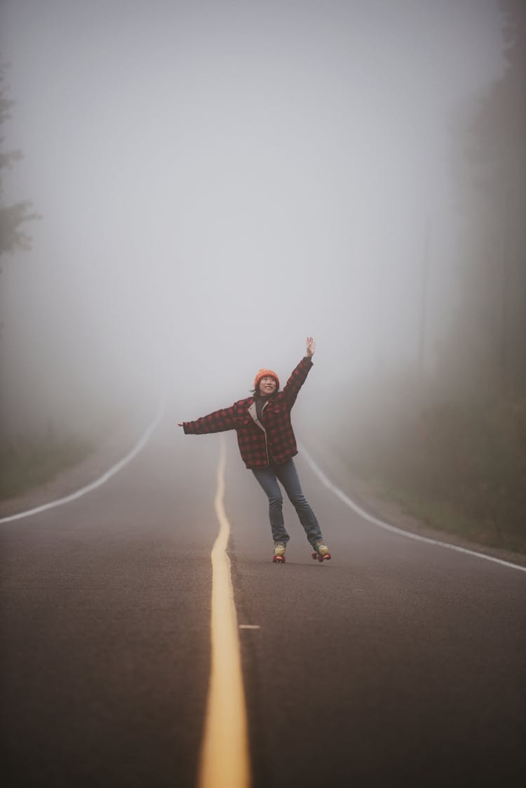 Cheerful Young Woman In Warm Clothes Skating On Road