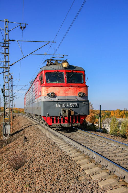 Red Train on Rail Tracks Under Blue Sky