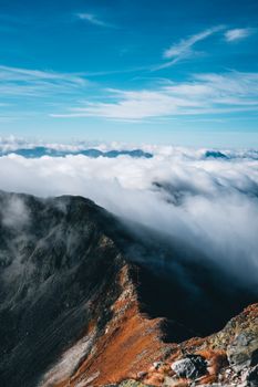 Breathtaking view of a mountain peak rising above the clouds with blue skies.