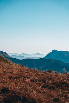 Breathtaking mountain range with clear blue sky and rolling hills. Ideal for nature lovers.