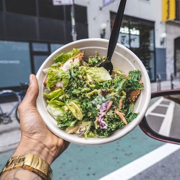 Healthy fresh salad held outdoors in New York City, highlighting nutritious ingredients and vibrant urban setting.