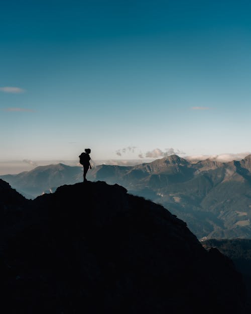 Free Silhouette of Man Standing on a Cliff  Stock Photo