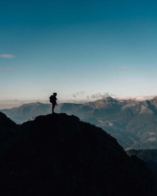 Free A lone hiker silhouette explores a mountain peak under a clear blue sky, evoking adventure and wanderlust. Stock Photo