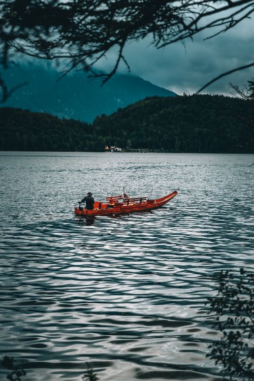Man Riding a Red Wooden Boat on Body of Water · Free Stock Photo