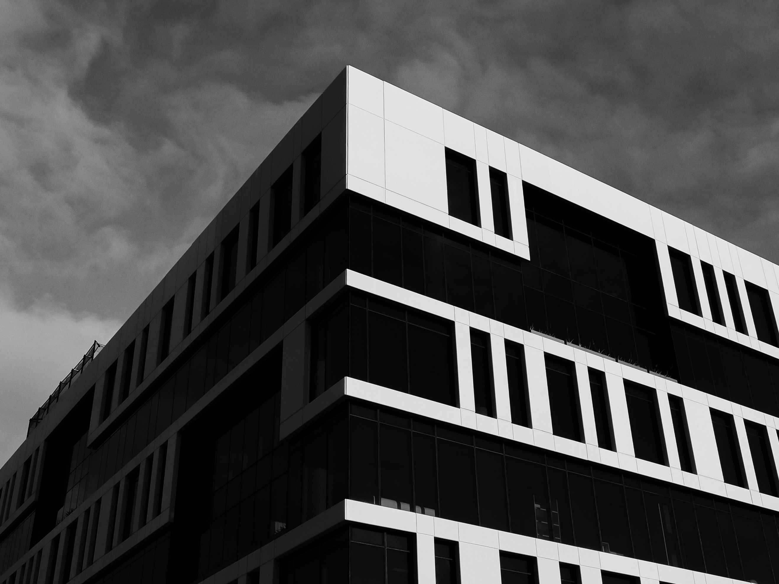 Striking black and white image of a modern building with glass windows and geometric design.