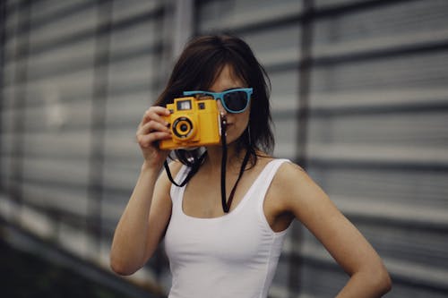 Woman in White Tank Top Holding Camera