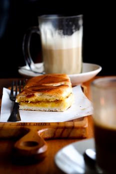 Delicious close-up of a pastry with coffee on a wooden board, perfect for breakfast themes.