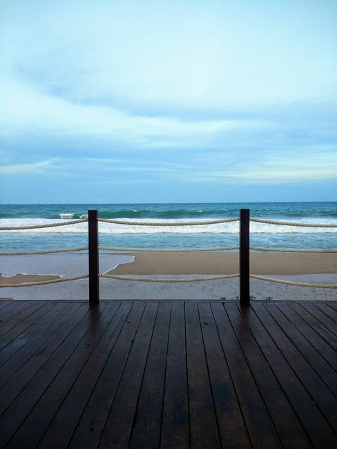 Photo by Larissa Ferreira on Pexels Peaceful ocean view from a wooden deck with rope railing, creating a scenic maritime setting.