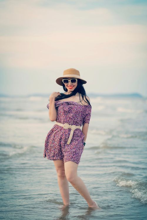 Free Woman in floral dress and hat smiling at the beach on a sunny day. Stock Photo
