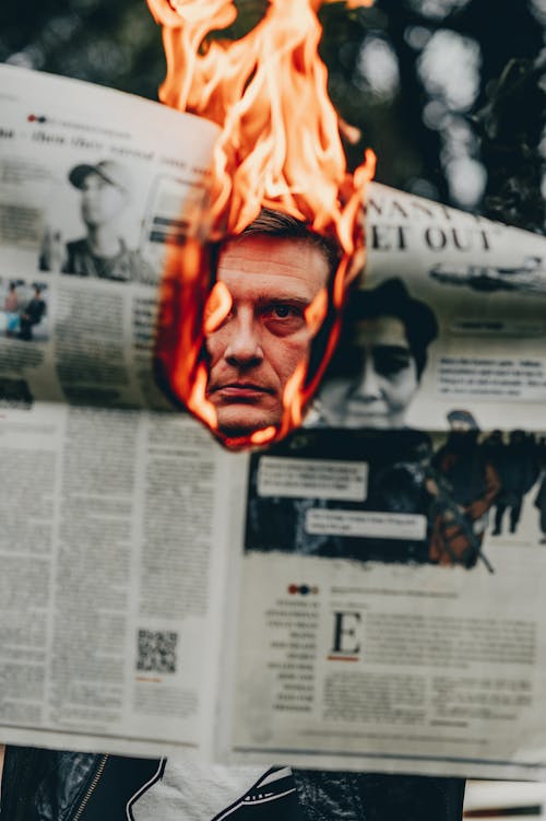 Free Burning newspaper revealing man face on other side Stock Photo