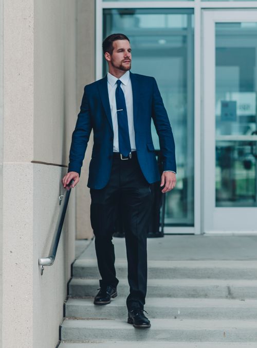 Free Businessman in blue suit confidently walks down steps outdoors. Stock Photo