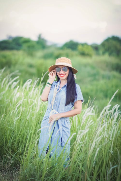 Happy Woman in Blue Dress Standing Near Grass