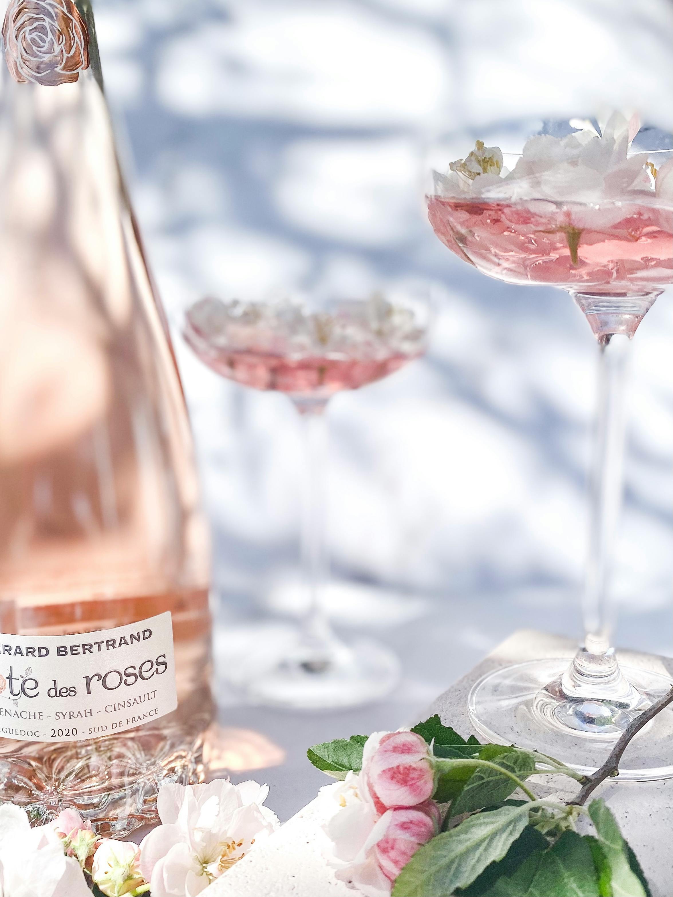 photograph of glasses with pink wine and flowers