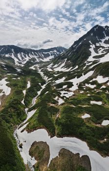 Breathtaking aerial view of Kamchatka's snow-capped mountains and valleys in summer.