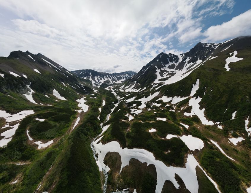 A stunning aerial view of snowy mountains and green landscapes in Kamchatka, Russia.