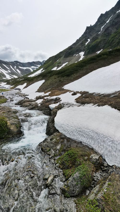 Free A picturesque mountain stream flowing through snow-covered terrain, showcasing nature's beauty. Stock Photo