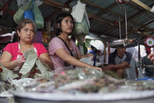 Free Two women selling goods at a bustling traditional market stall. Stock Photo