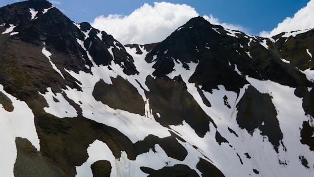 Snow-covered volcanic peaks under a clear blue sky in Kamchatka, Russia.