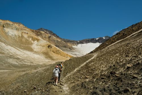 Free Group of hikers ascending a rocky mountain trail under a clear blue sky. Stock Photo