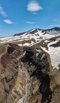 Stunning aerial shot of Kamchatka's snow-capped mountain ranges, showcasing rugged natural beauty.