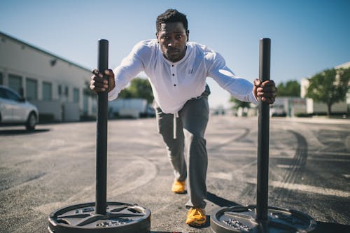 Man Wearing White Long-sleeved Shirt Pushing Two Black Barbells