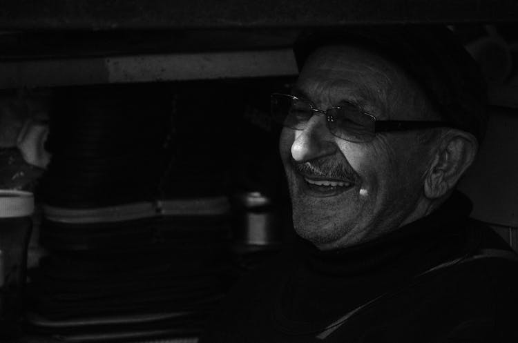 Grayscale Photo Of An Elderly Man Laughing