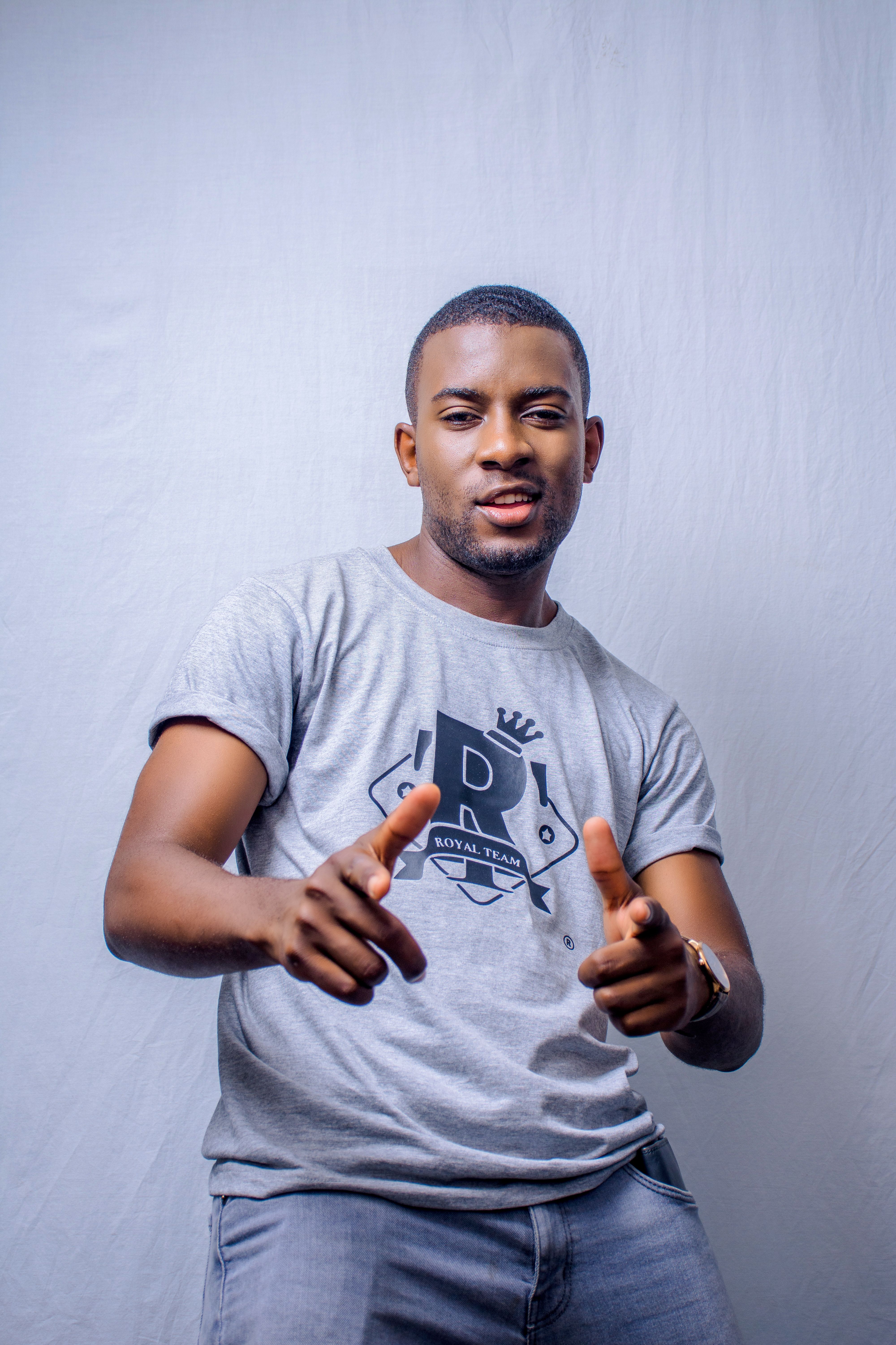 Confident young man with short hair pointing and smiling in a casual pose.