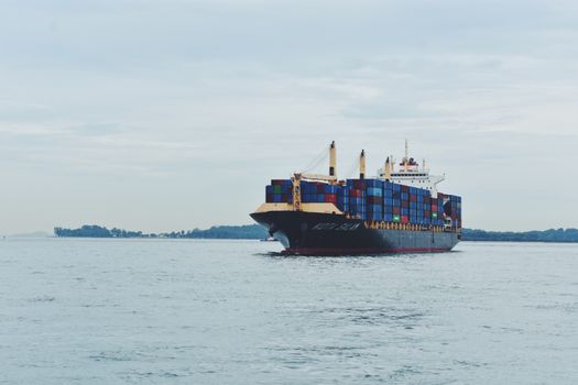 Large cargo ship transporting containers across a calm sea, symbolizing global logistics.