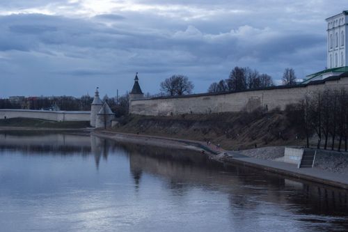 Free Scenic view of Pskov Kremlin and surrounding walls reflecting in the calm river. Stock Photo