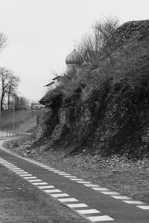Free Curved road beside a cliff in a tranquil countryside setting, captured in black and white. Stock Photo