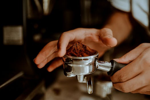 Close-up of a barista preparing fresh coffee grounds in a portafilter for espresso making.