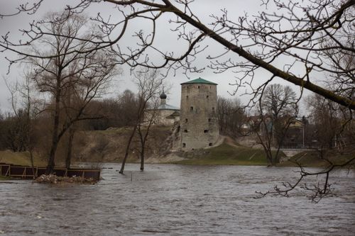 Free Historic tower by a flooded river with bare trees and cloudy sky in early spring. Stock Photo