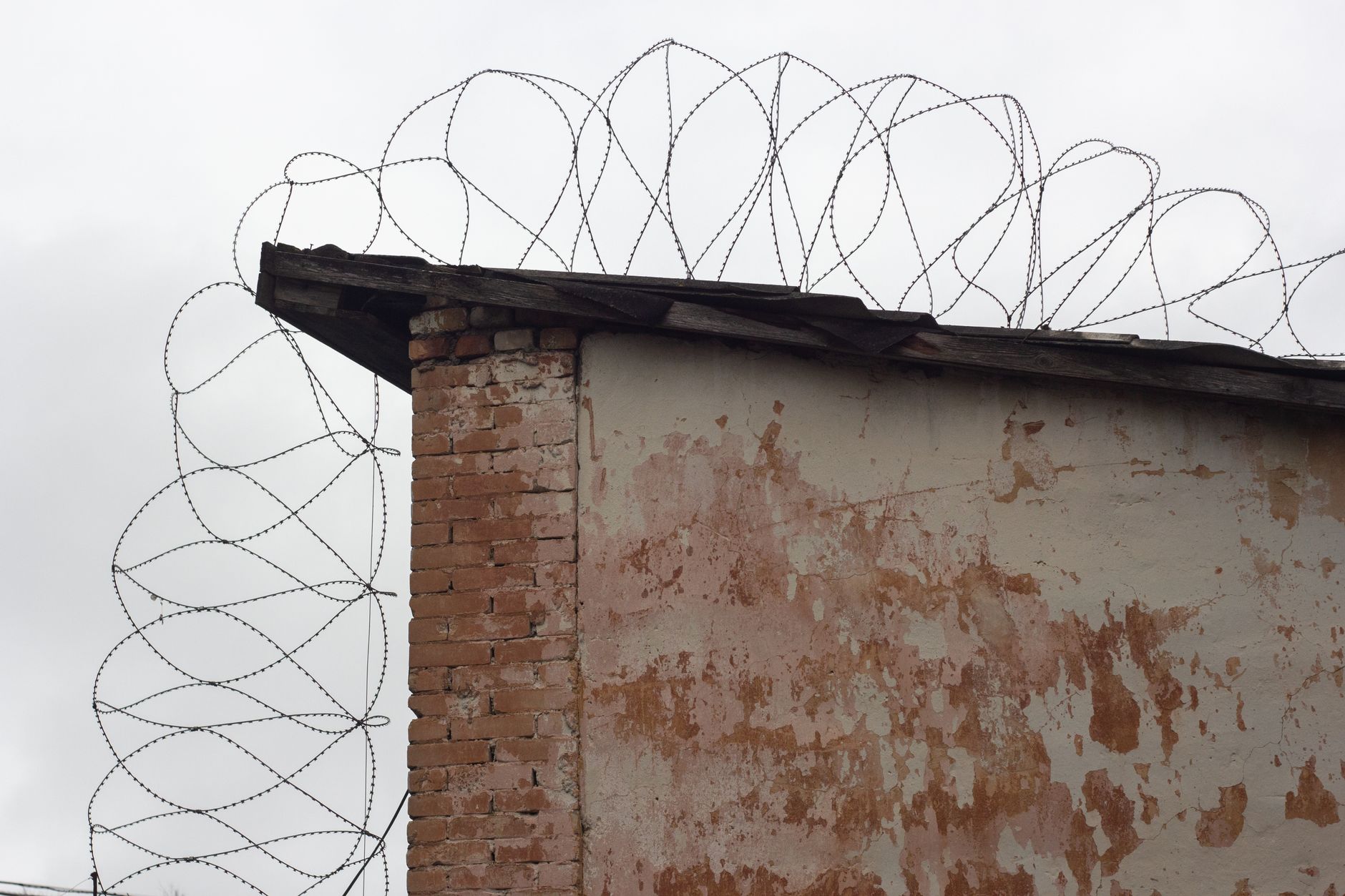 A close-up of a weathered building with barbed wire, showcasing security themes.