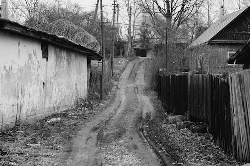 Free Grayscale Photograph of a Dirt Road Between Buildings Stock Photo