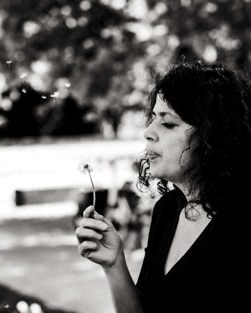Free Grayscale Photo of a Woman Blowing Dandelion Flower Stock Photo